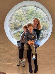 Lucy smiling sitting in a window with her sons