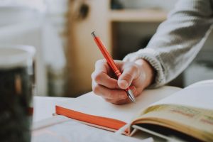 a woman's hand holding a pen writing in a notebook